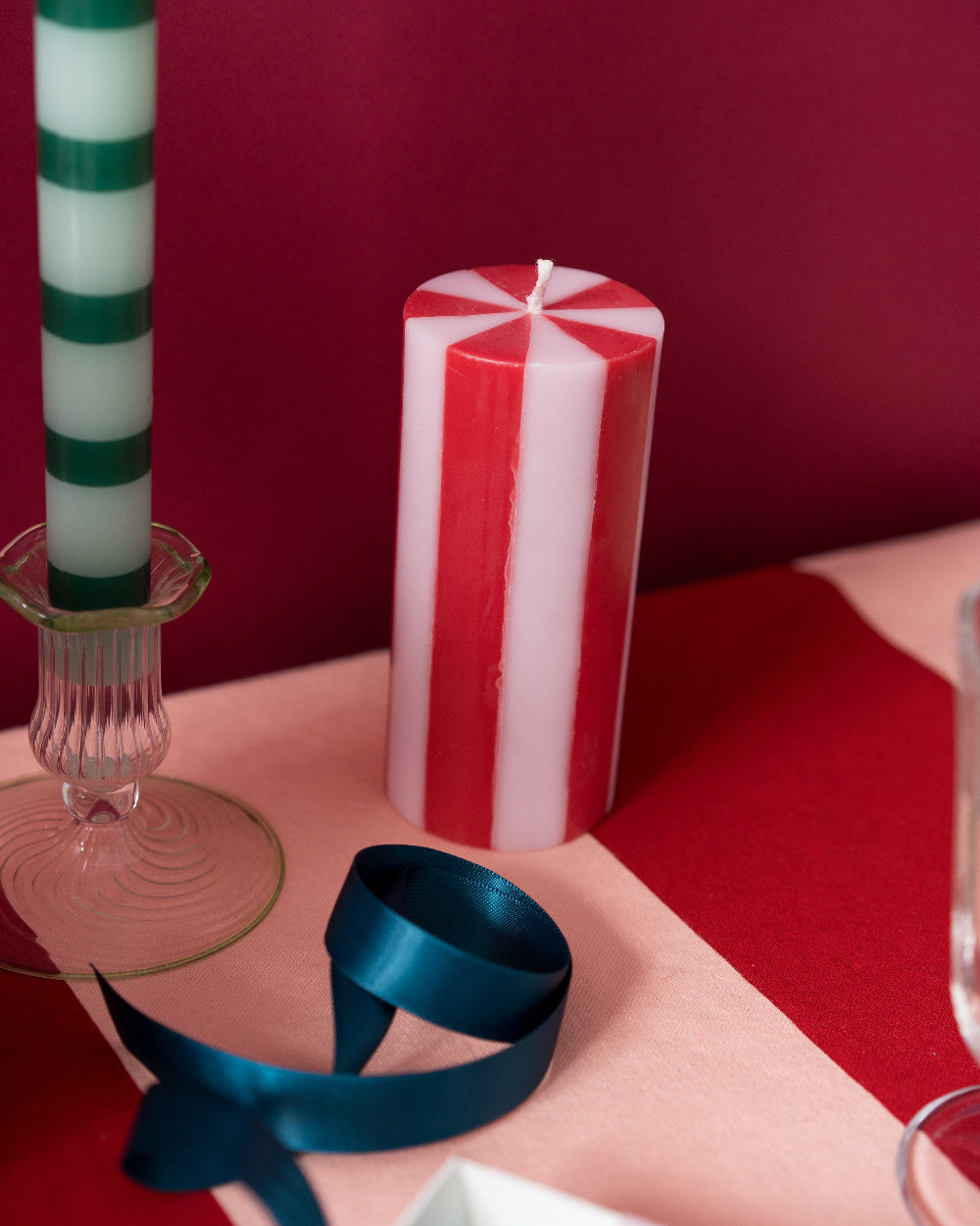 Decorative candles with a blue ribbon on a red surface